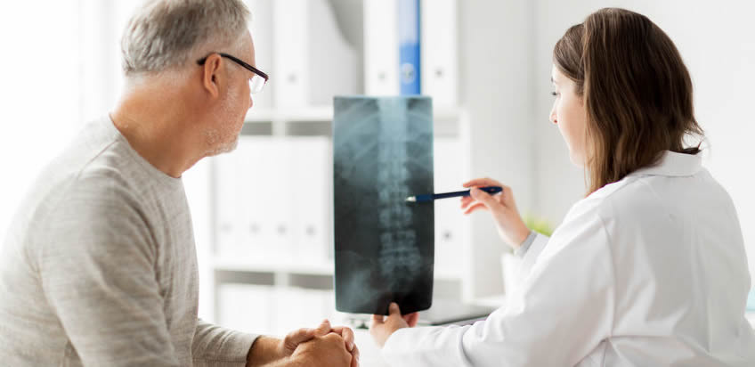 Doctor showing x-ray of spine to senior man.