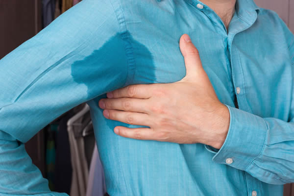 Man with sweaty armpit and a wet spot on his shirt.