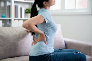 Young woman on couch with back pain.