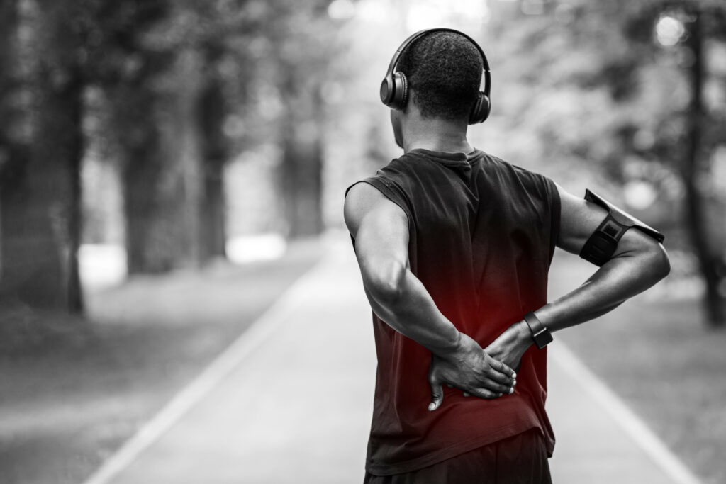 Back view of man in sportswear touching injured back